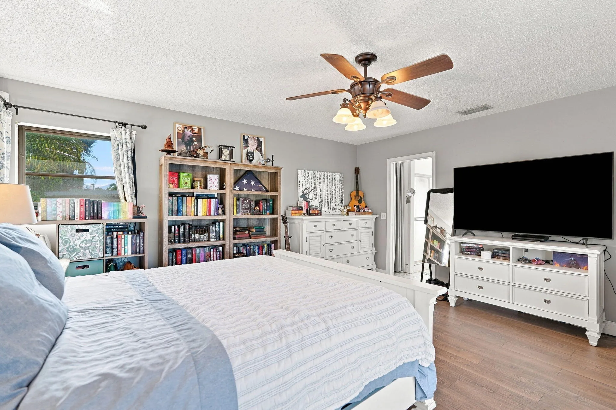 LVP flooring, ceiling fan with integrated lighting, window with ample natural light and a neutral wall color