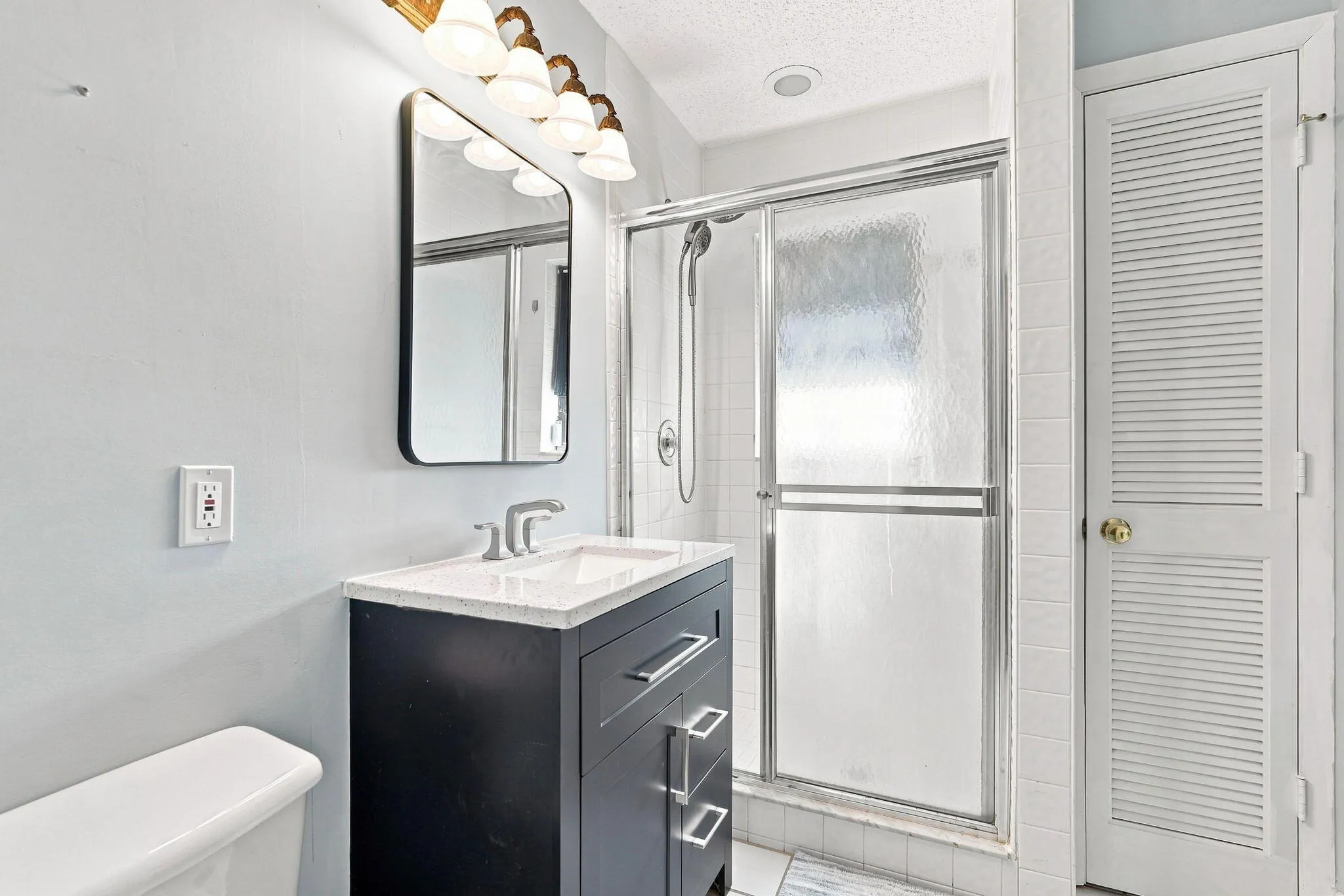 Vanity with white countertop, chrome faucet and rectangular mirror