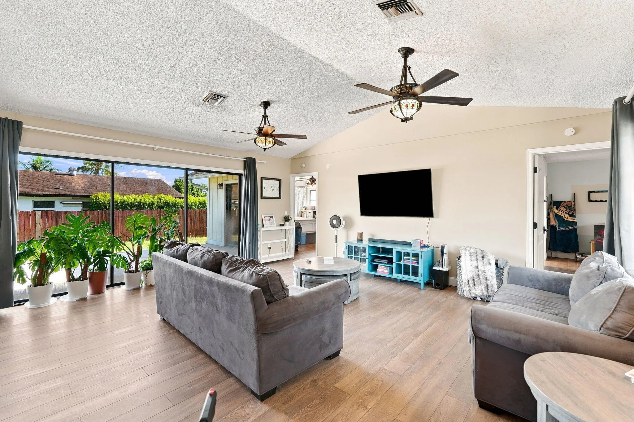 Spacious living area featuring LVP flooring, vaulted ceilings and dual ceiling fans