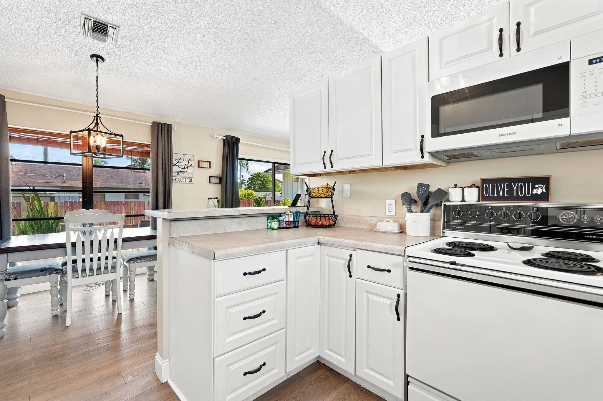 White cabinetry, solid surface countertops, built-in microwave and LVP flooring