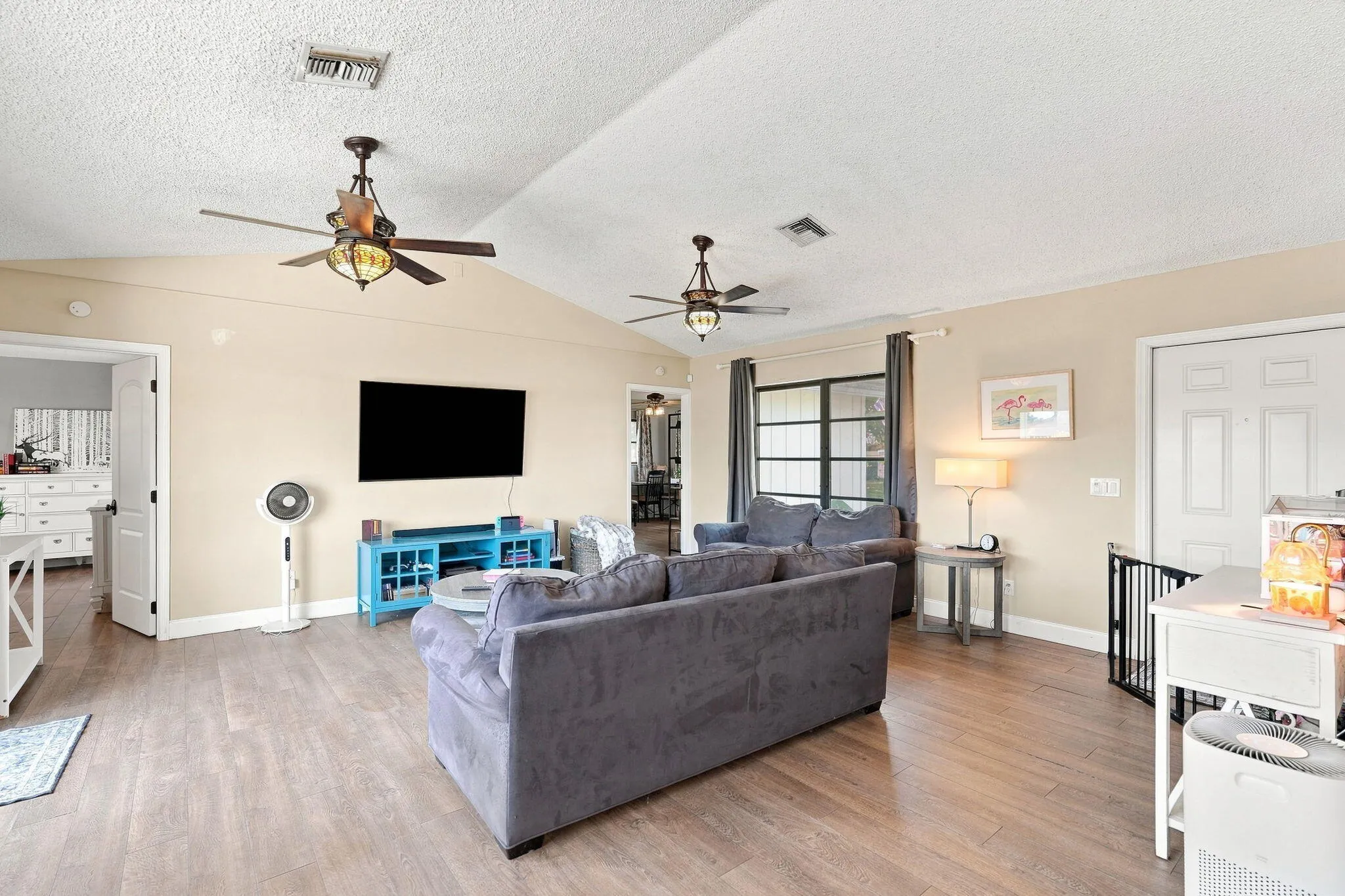 Vaulted ceiling, LVP flooring, ceiling fans with lighting, window with grid pattern and white interior doors