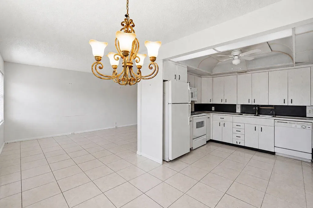 Open-concept kitchen and living area featuring tile flooring, white cabinetry, and a ceiling fan