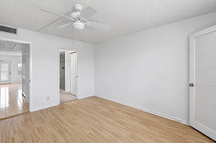 Wood-finish flooring, white walls, and a ceiling fan