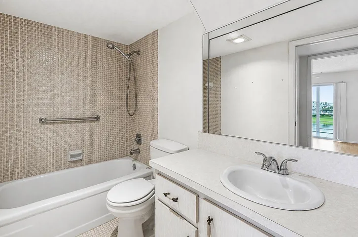 White bathtub with a chrome shower head and mosaic tile surround