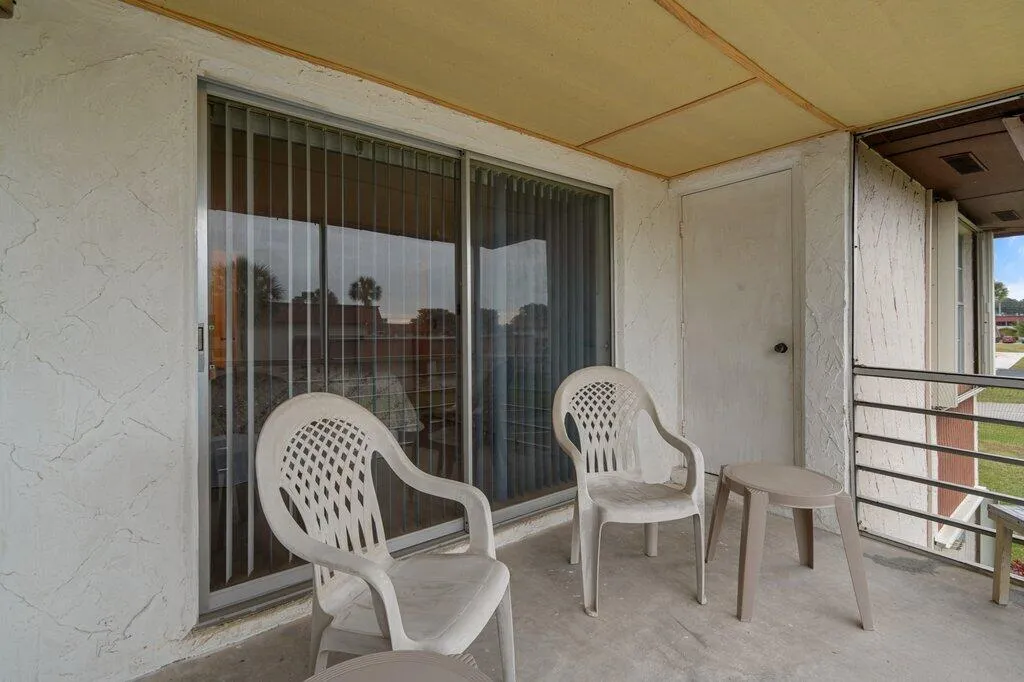 Private balcony with textured exterior walls, concrete flooring, and metal railings