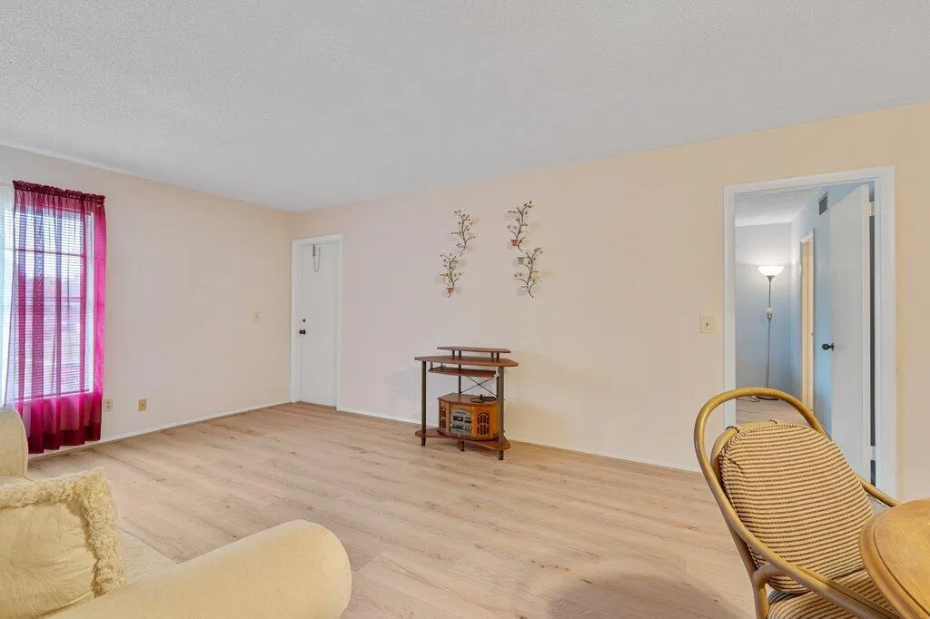 Wood-finish LVP flooring throughout, light-toned walls, and a window with sheer and solid panels