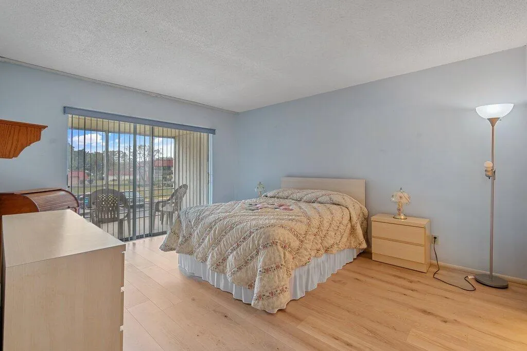 Light wood-finish LVP flooring, sliding glass door with vertical blinds, wall-mounted wooden shelf, and smooth ceilings