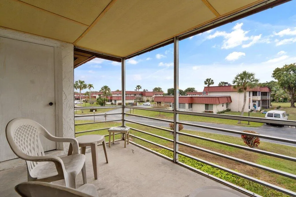 Screened porch with a textured ceiling, concrete flooring, and metal railings
