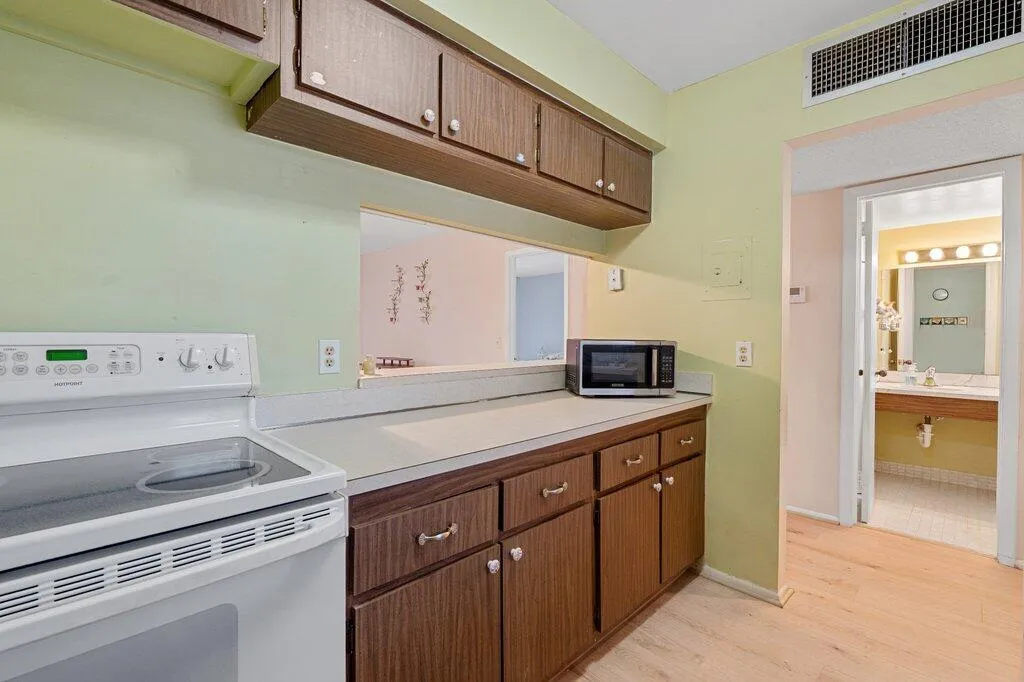 Kitchen featuring wood-finish cabinetry, solid surface countertops, and a pass-through window