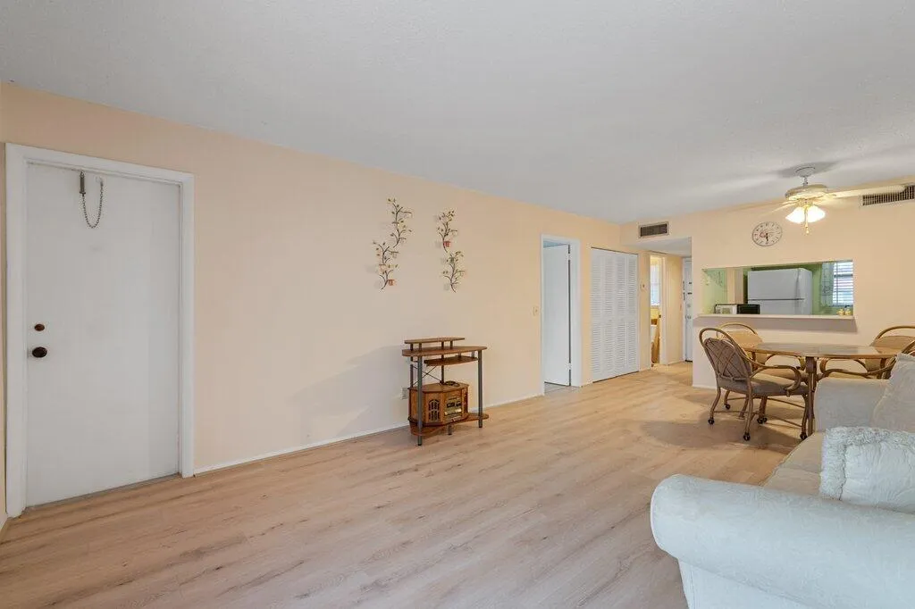 Expansive living area with wood-finish flooring, a ceiling fan, and a pass-through counter