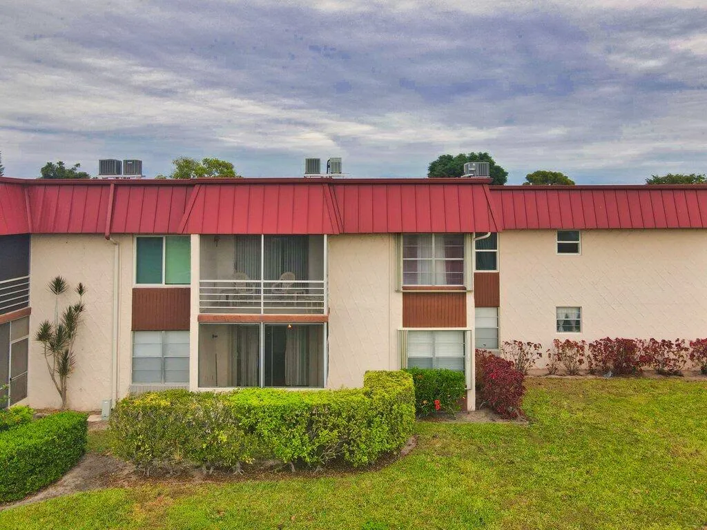 Two-story building with a red metal roof and textured exterior finish