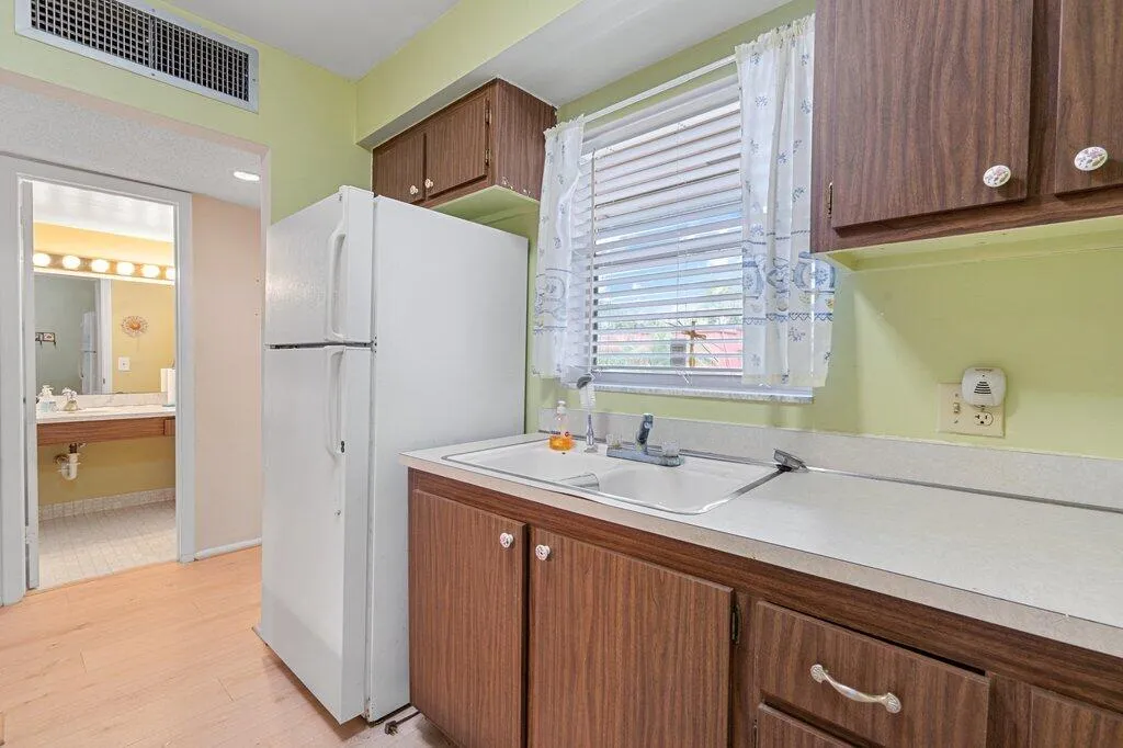 Kitchen featuring wood-finish cabinetry, a double basin sink, and a window with blinds