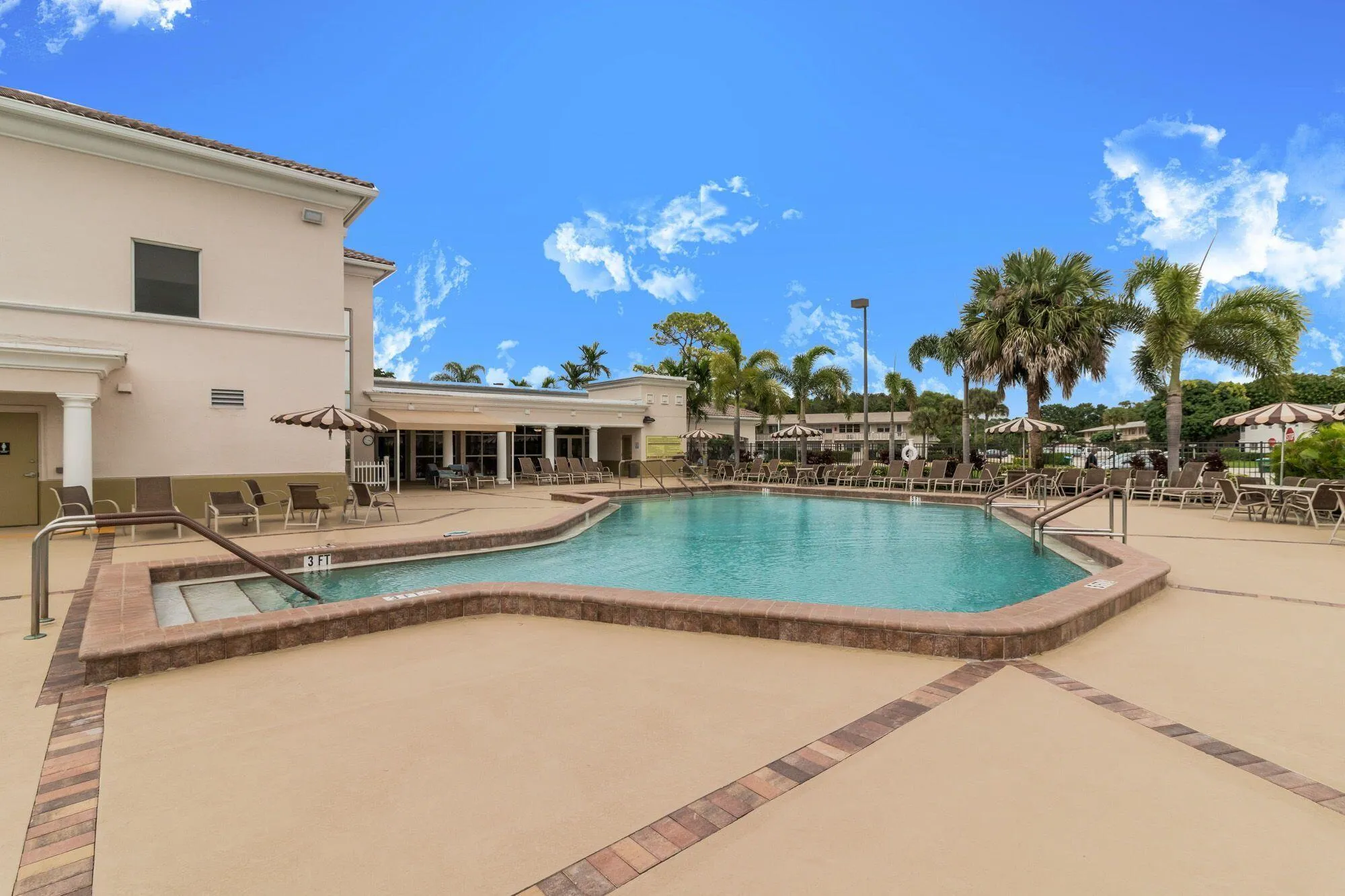 Expansive outdoor swimming pool with integrated spa and surrounding paver deck