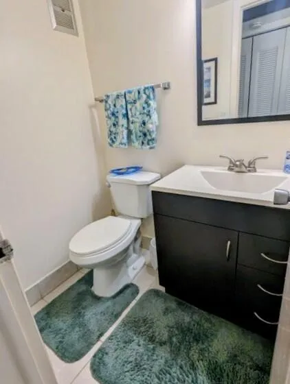 White toilet with a dark vanity featuring a white sink and chrome faucet