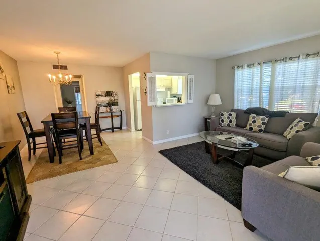 Tiled flooring throughout, dining area with chandelier, pass-through window, and multiple windows