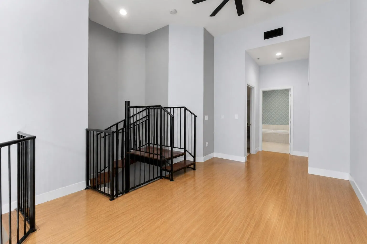 Hardwood flooring, iron staircase with wood treads, recessed lighting, ceiling fan, and high ceilings