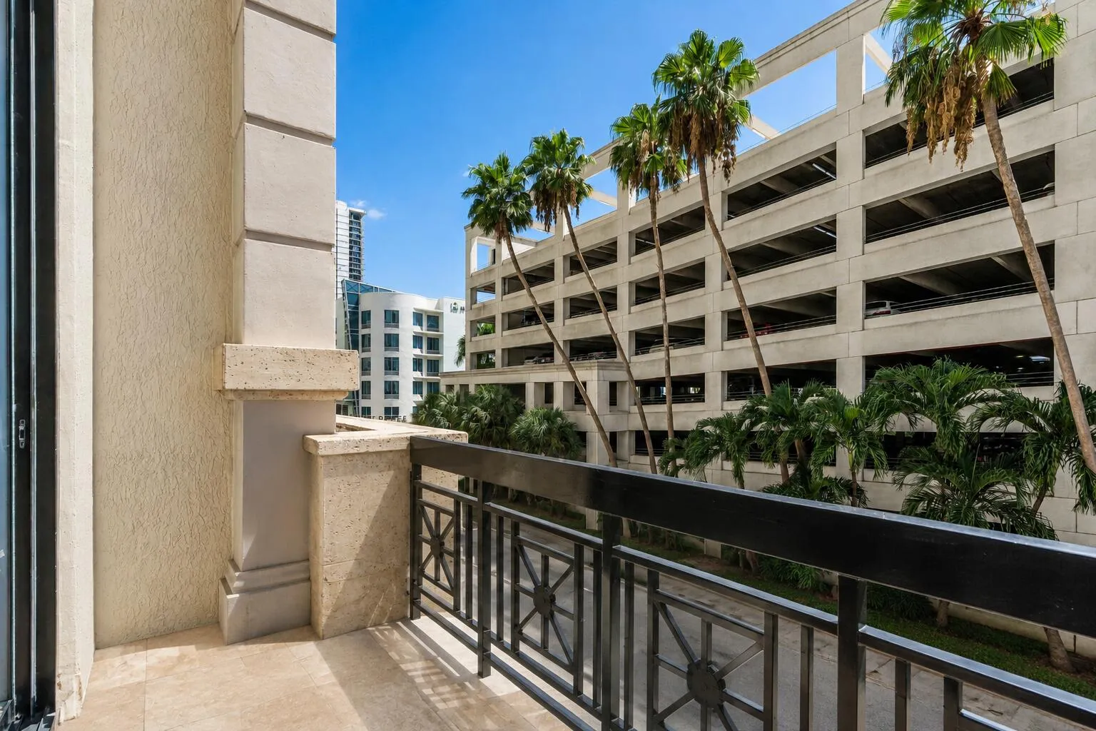 Balcony with stone flooring, decorative metal railing, and textured exterior walls