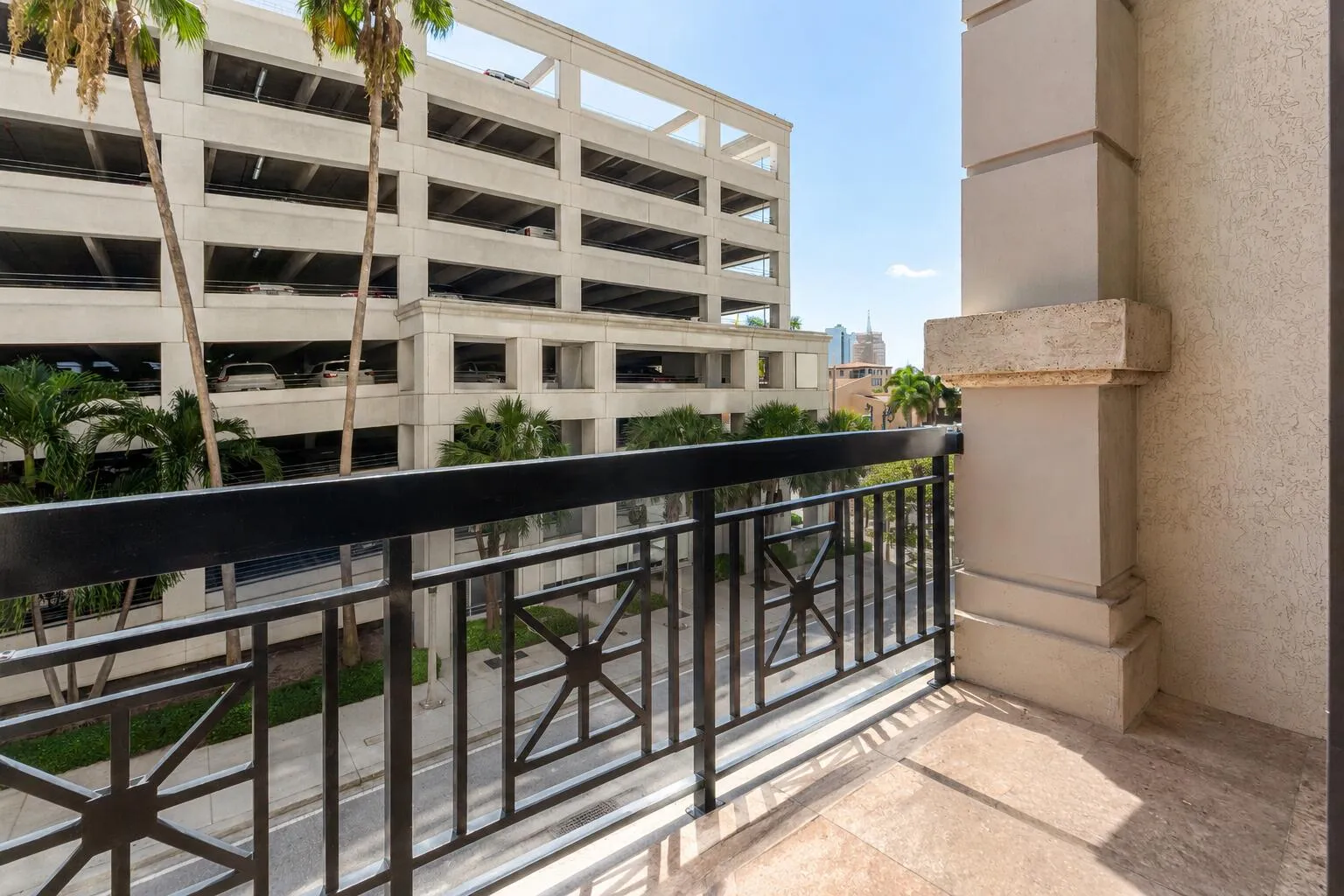 Balcony featuring an ornate metal railing, tile flooring, and column detailing
