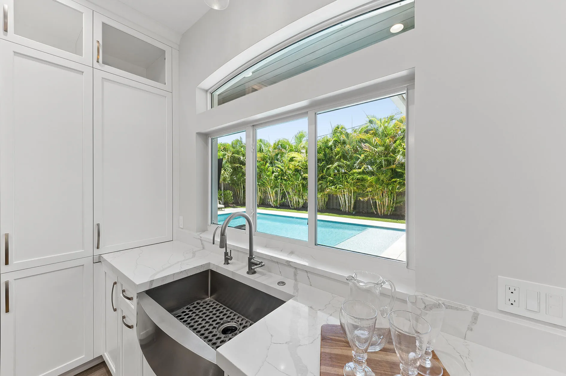 Large Apron Sink overlooking sparkling pool and pass through window