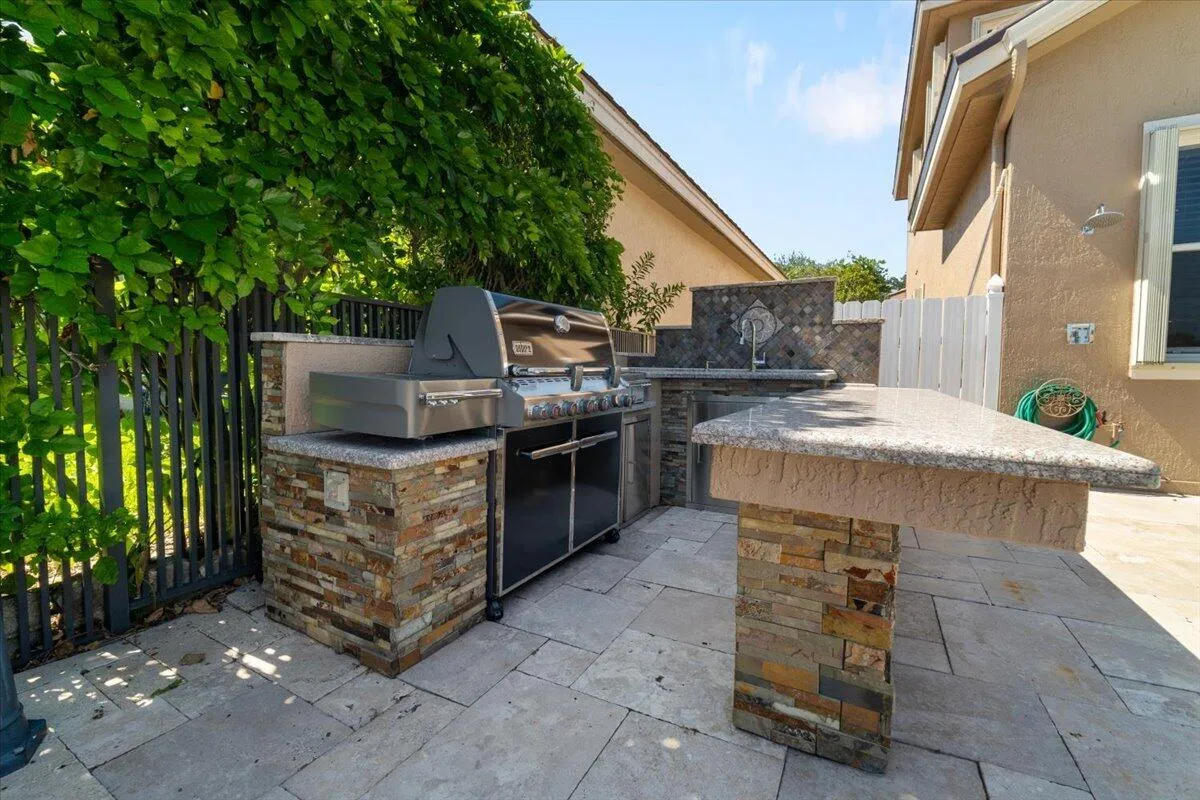 This stone custom summer kitchen with built in BBQ & sink and fridge