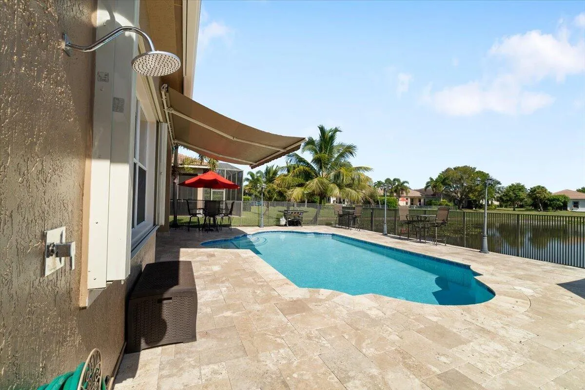 come and take a swim in this cool pool in our fully fenced Jerusalem travetine paved patio, Notice the strong top of the line hurricane impact accordion quick shutters,
