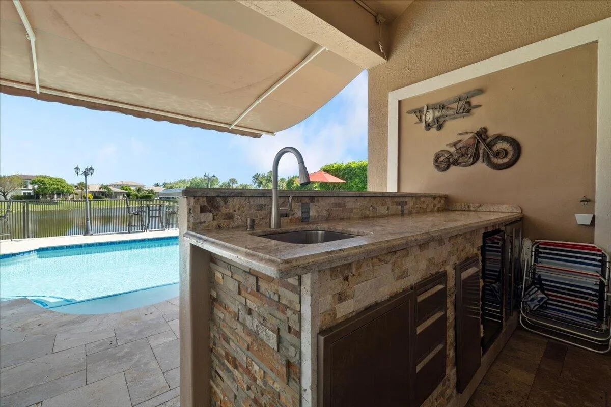 The Outside stone built cocktail bar with stainless sink and all top of the line plumbing chrome fixtures and faucests, Stainless wine cooler/fridge & sink, Granite Bar top, A beautiful 18 x 10 foot electric remote controlled Retractable awning for cocktail shading & swimming, Crown moldings and custom wall enclose this cocktail bar area for full entertaiment