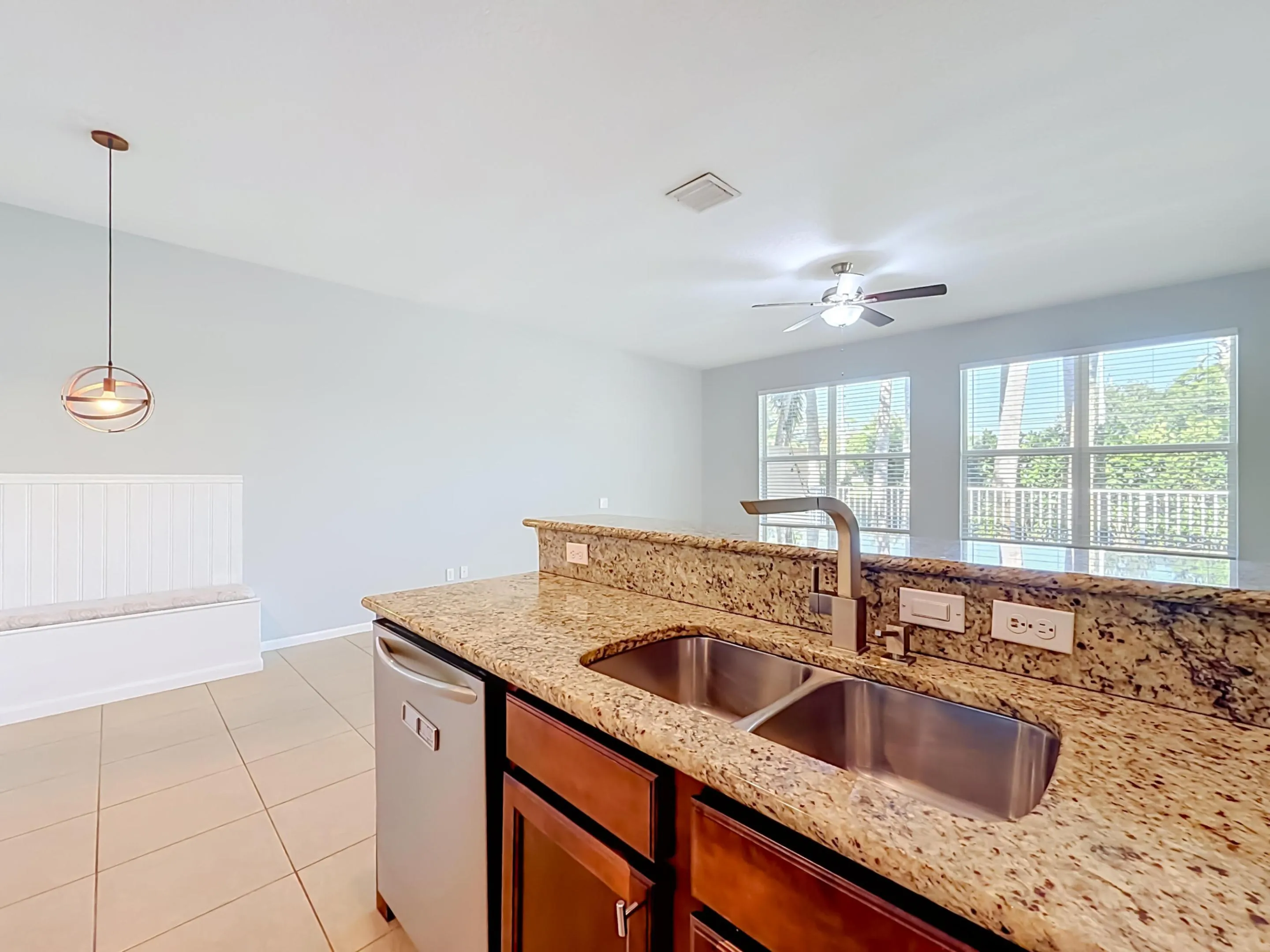 Kitchen island with a double basin stainless steel sink, granite countertops, and a stainless steel dishwasher