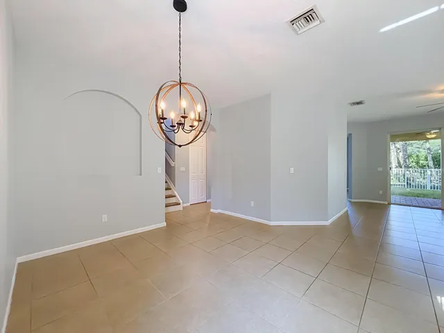 Open concept living space featuring neutral wall tones, tile flooring, and a contemporary chandelier