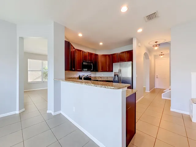 Kitchen featuring wood cabinetry, stainless steel appliances, and granite countertops with a breakfast bar
