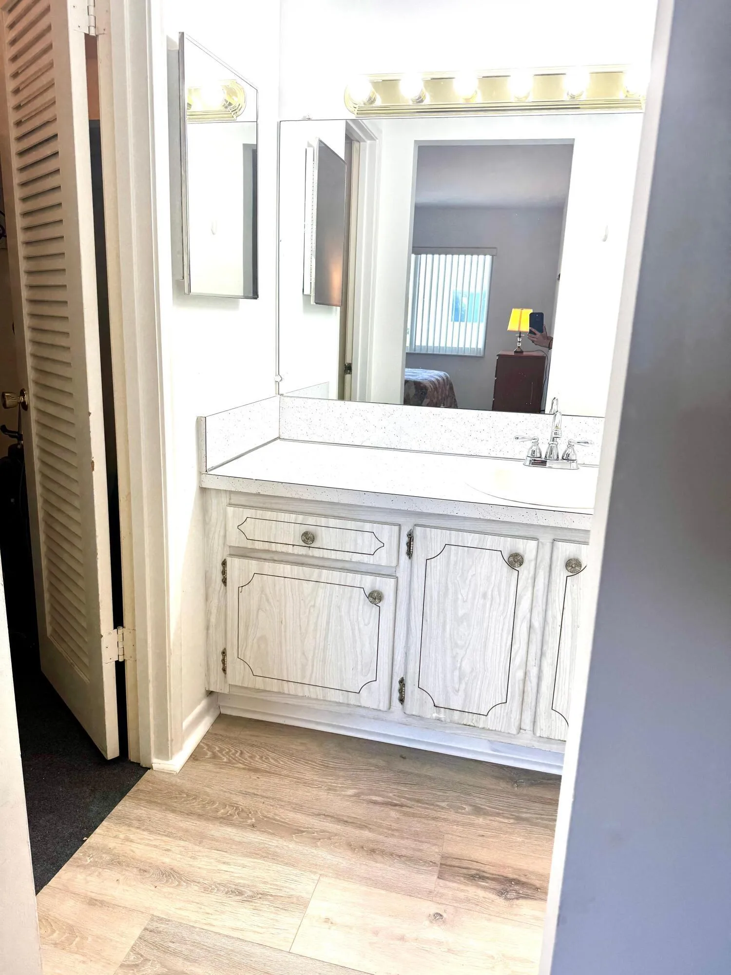 Bathroom vanity featuring a white countertop, wood-finish cabinetry, and a mirrored medicine cabinet