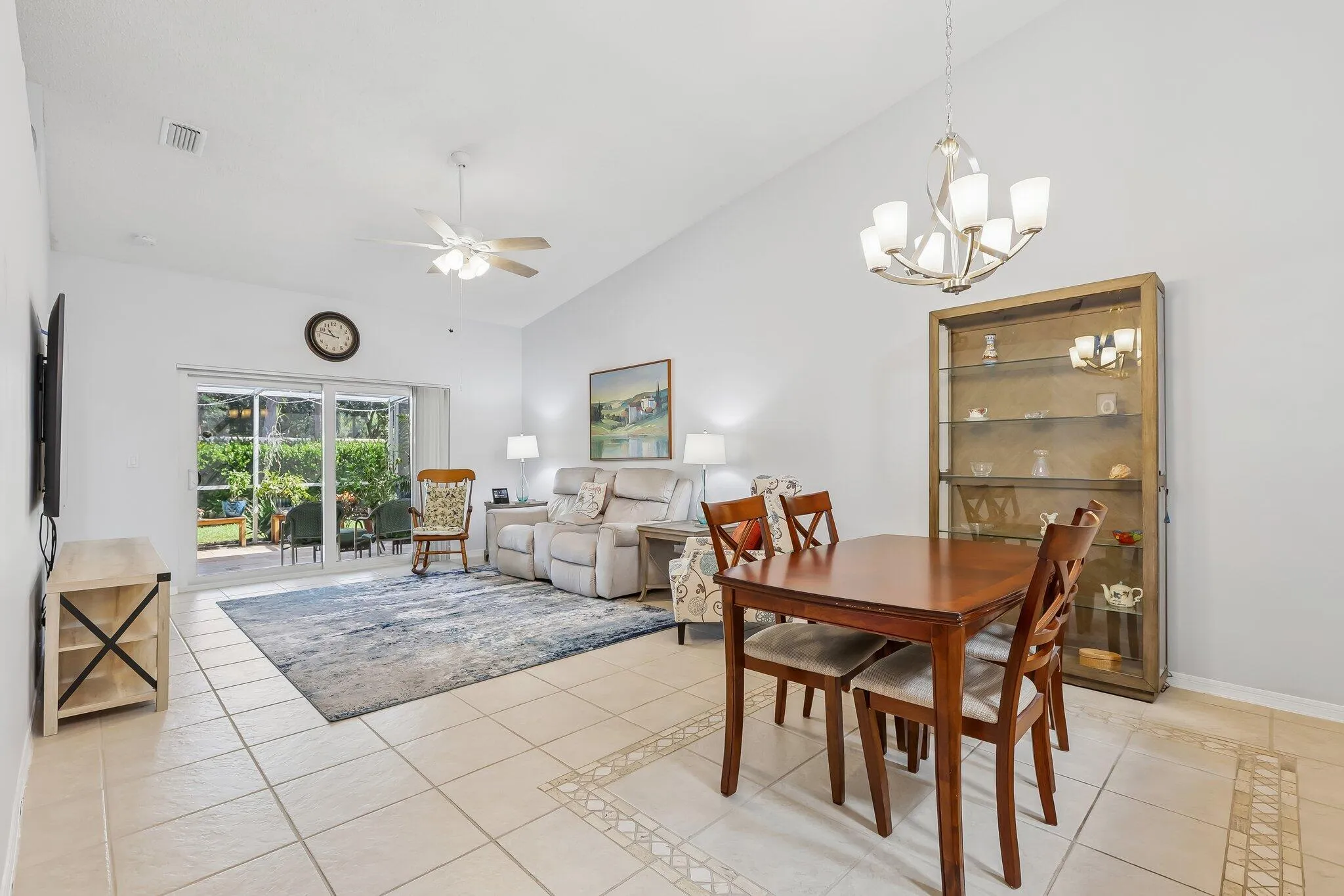 Vaulted ceilings, tile flooring with decorative inlay, sliding glass doors, and a ceiling fan