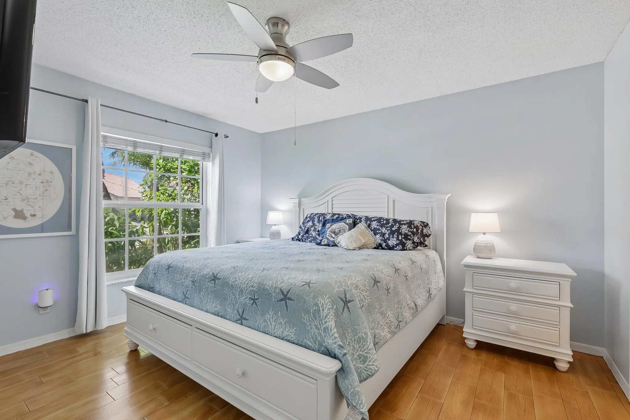 Wood-finish flooring, white window frame, and overhead ceiling fan