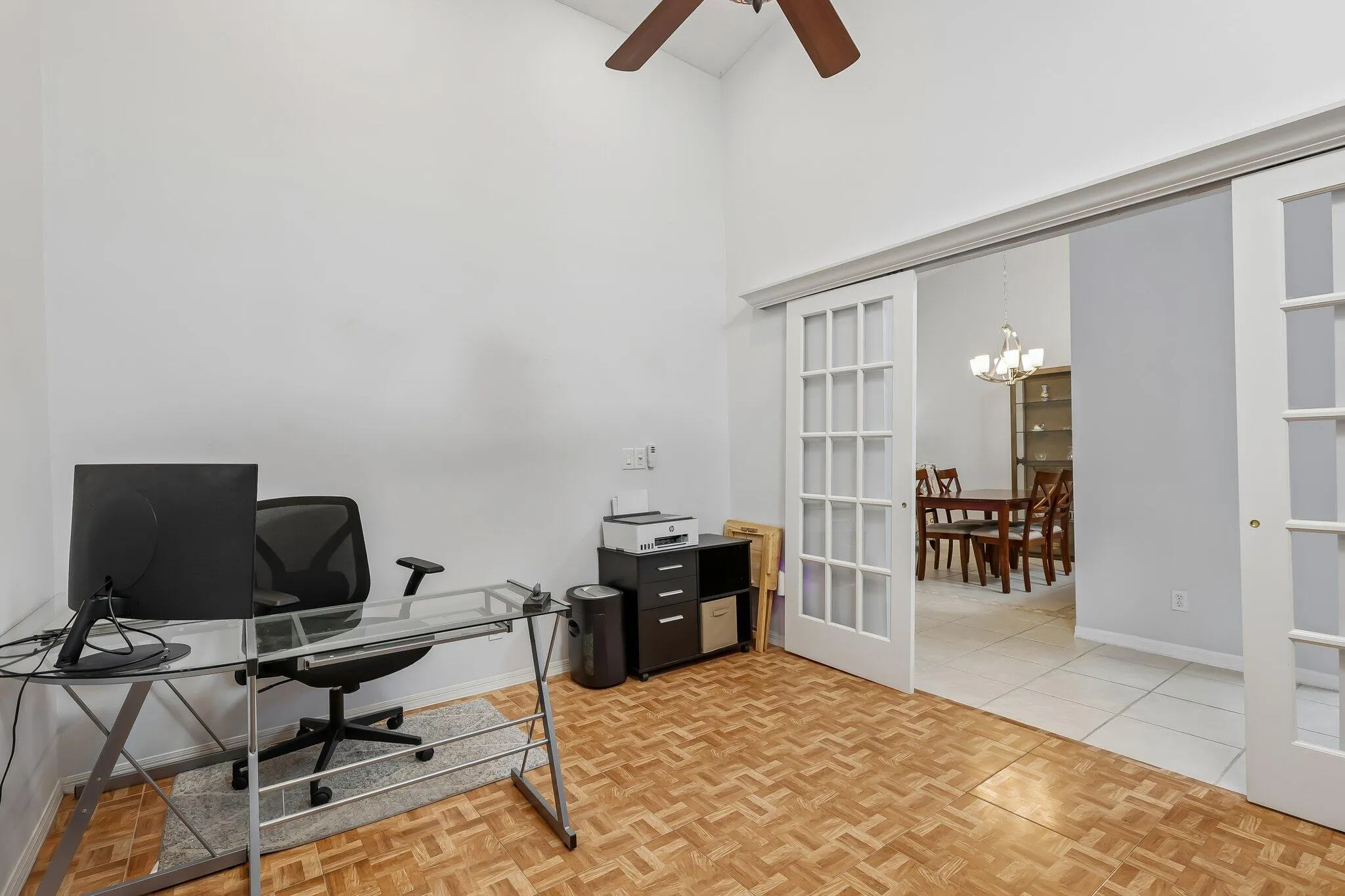 Vaulted ceiling, ceiling fan, wood-finish flooring, sliding French doors with grid-patterned lites, recessed lighting