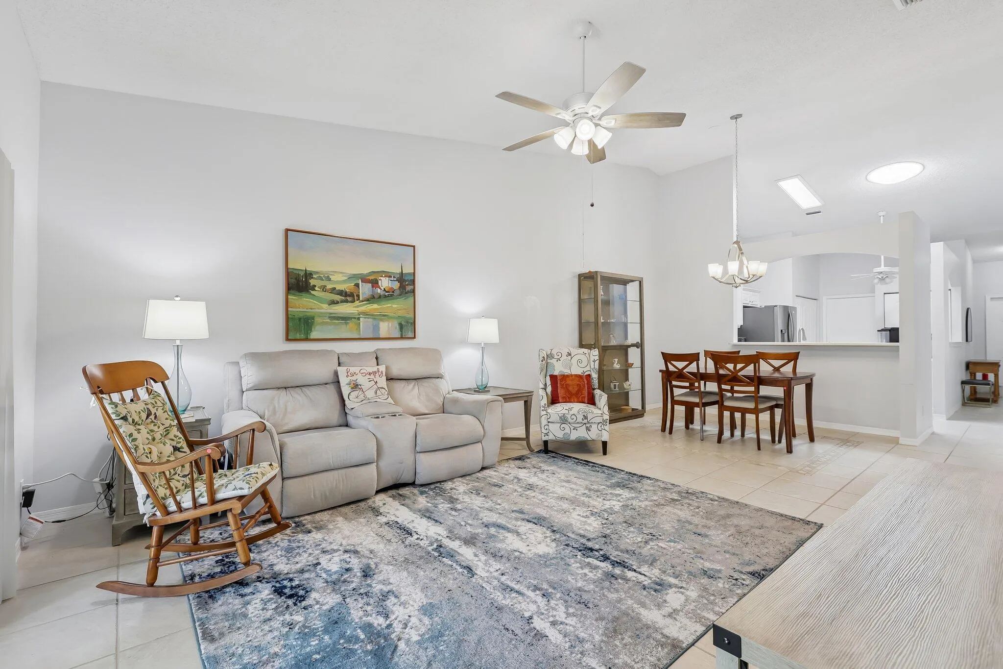 Open-concept living and dining area with high ceilings, ceiling fan, and tile flooring