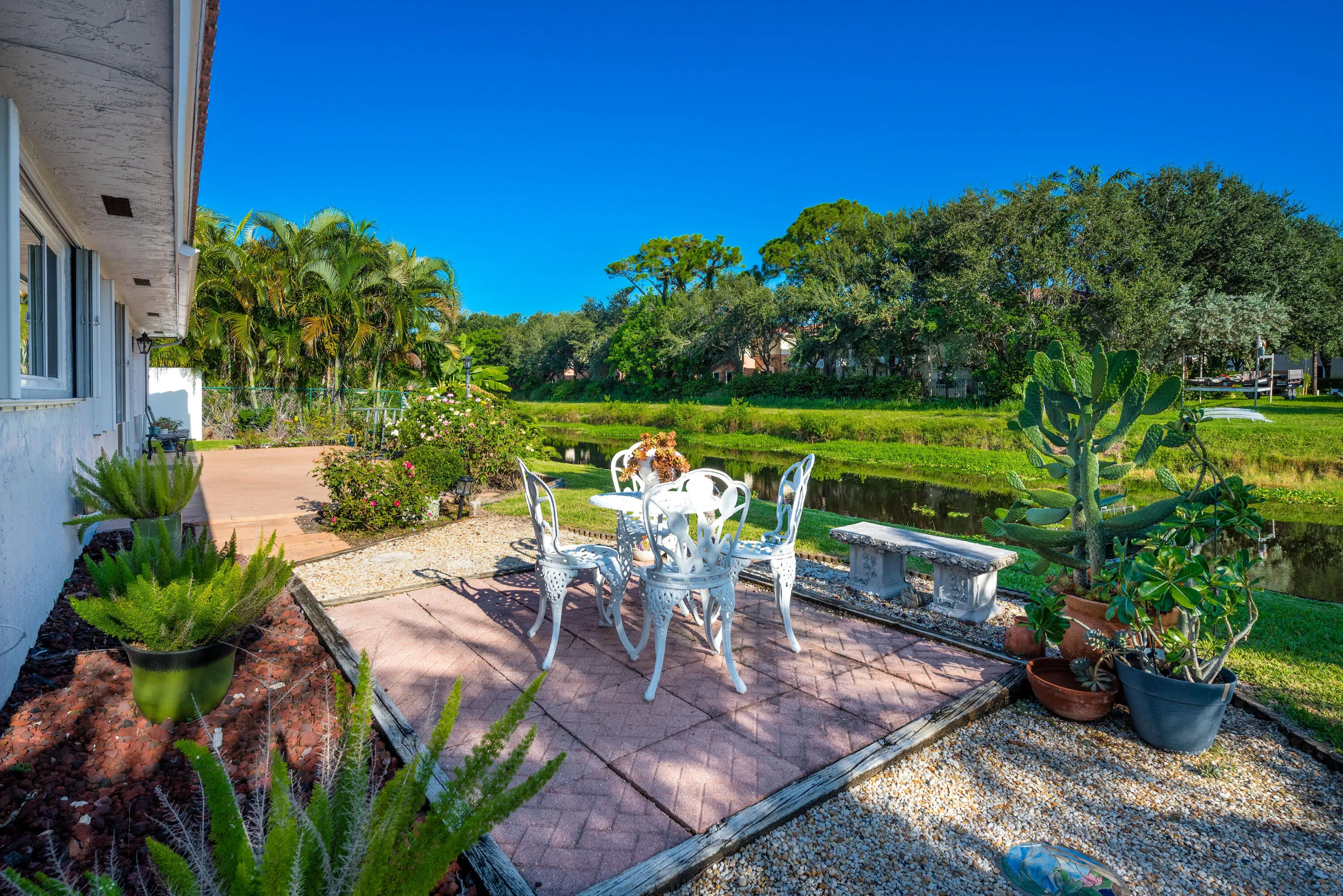 Patio area featuring brick pavers and gravel, with a water feature and lush landscaping