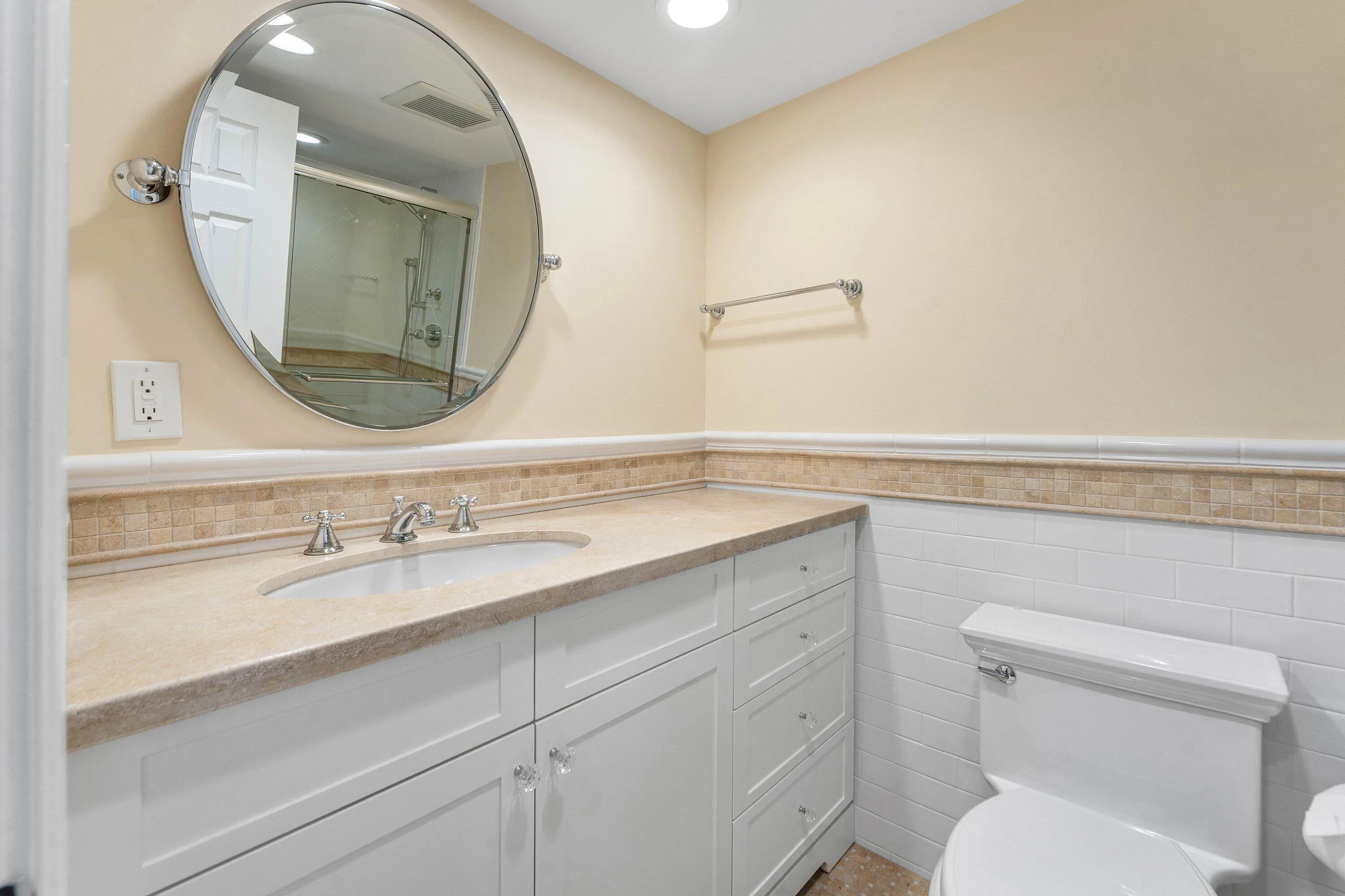 The second full bath includes a long vanity with abundant cabinet storage and a large wall mirror.