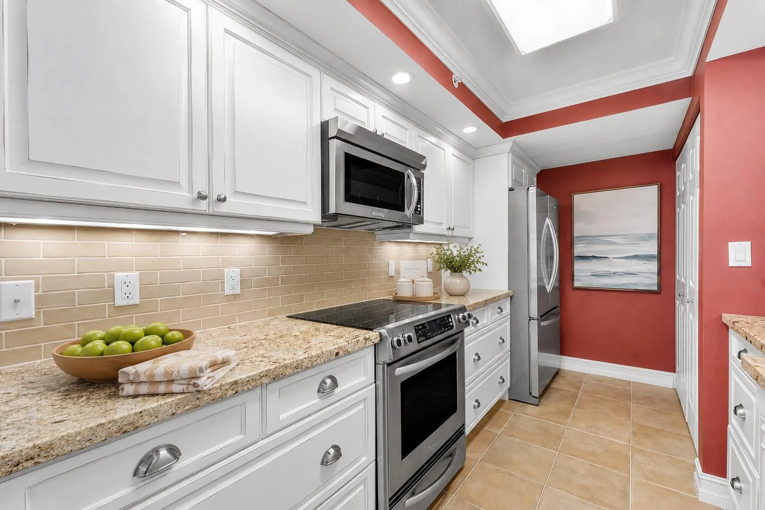 Kitchen highlights white cabinetry, granite countertops, tiled backsplash and stainless-finish appliances.