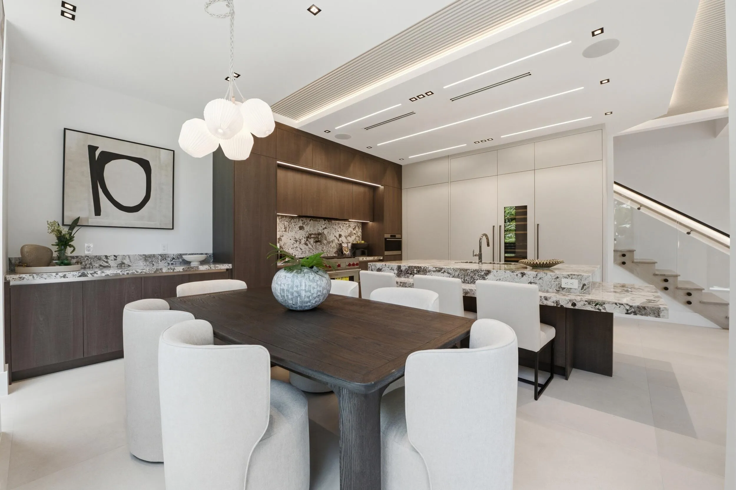 Integrated kitchen and dining area featuring a modern chandelier, recessed lighting, wood-finish cabinetry, and marble-look countertops