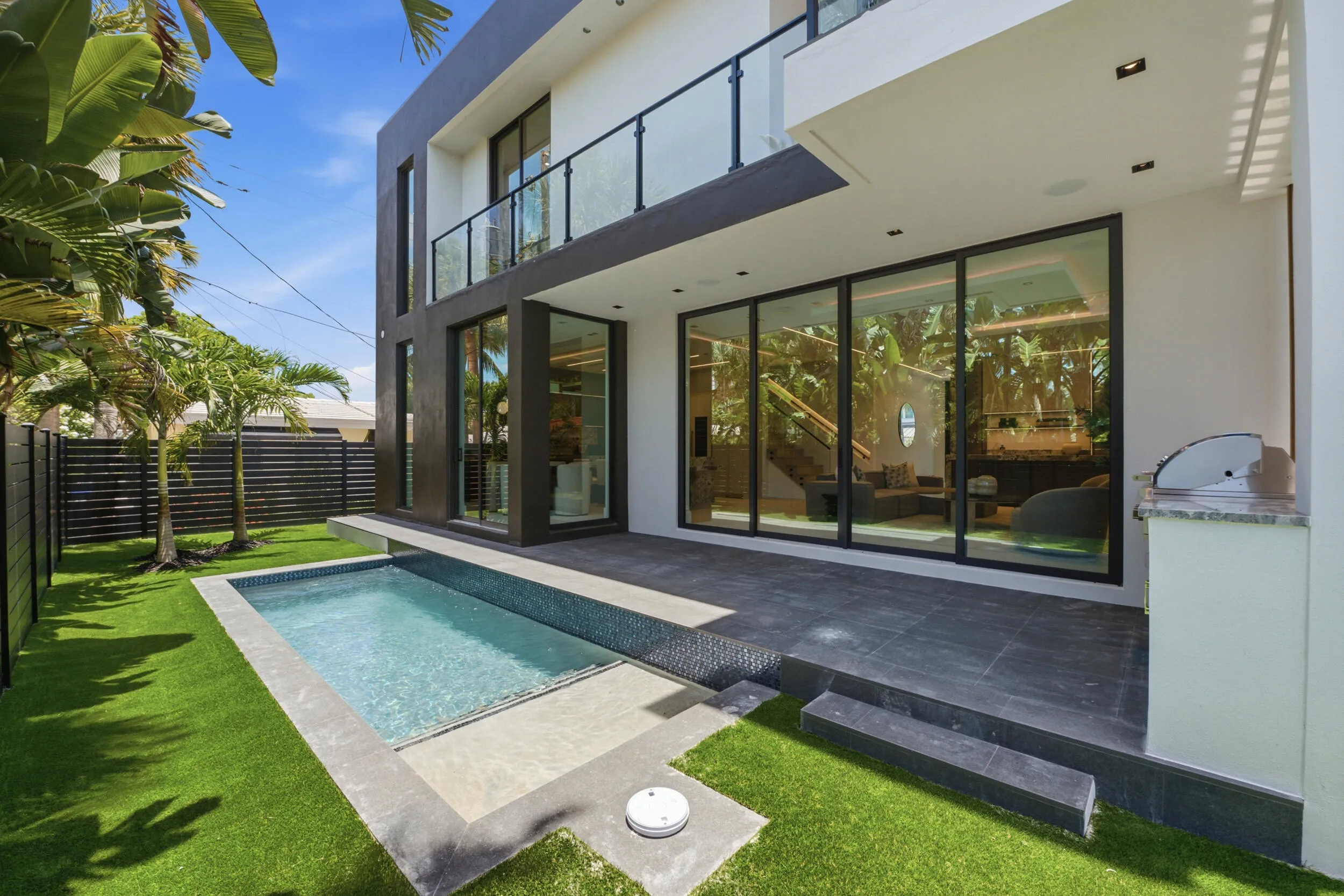 Modern exterior with a private swimming pool, expansive patio, artificial turf, and an outdoor grilling station