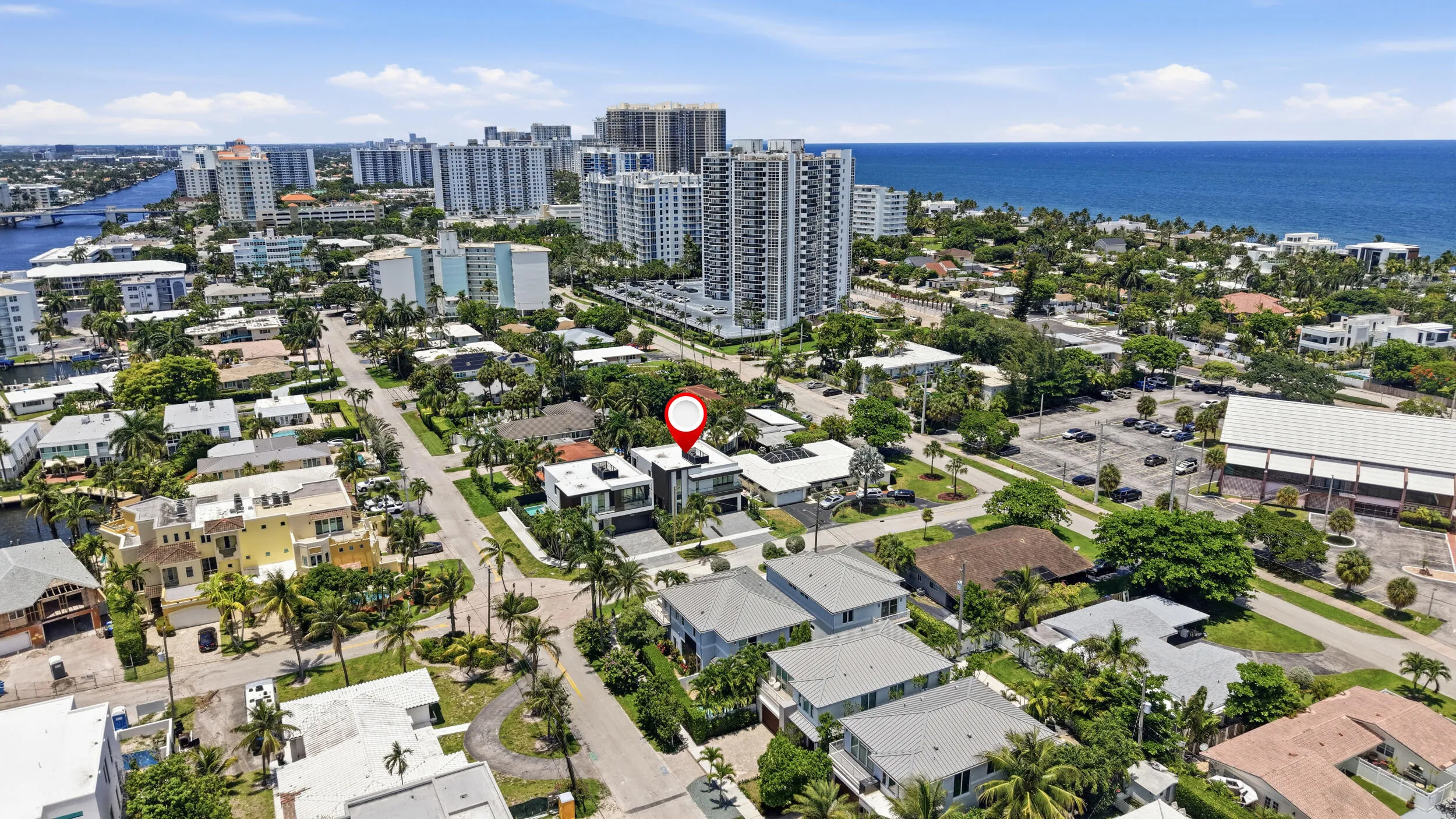Aerial perspective of this residential property showcasing mature landscaping with lush tropical vegetation, concrete driveways and hardscaping, and a metal roof structure