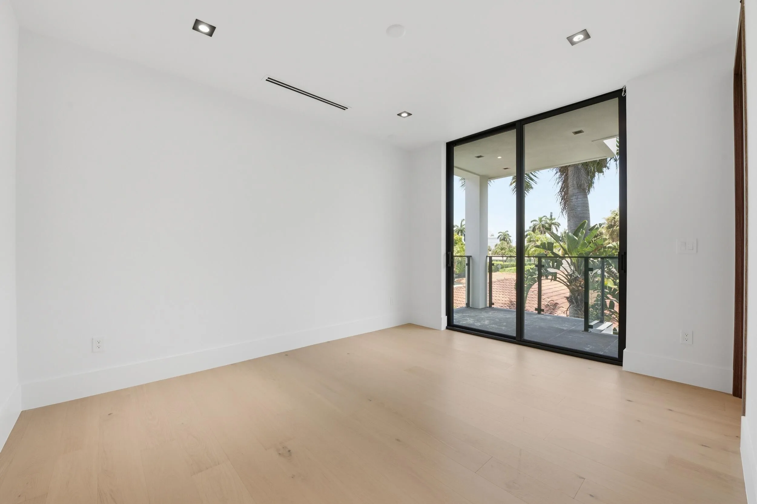 Hardwood-style flooring, recessed lighting, and a large sliding glass door with balcony access