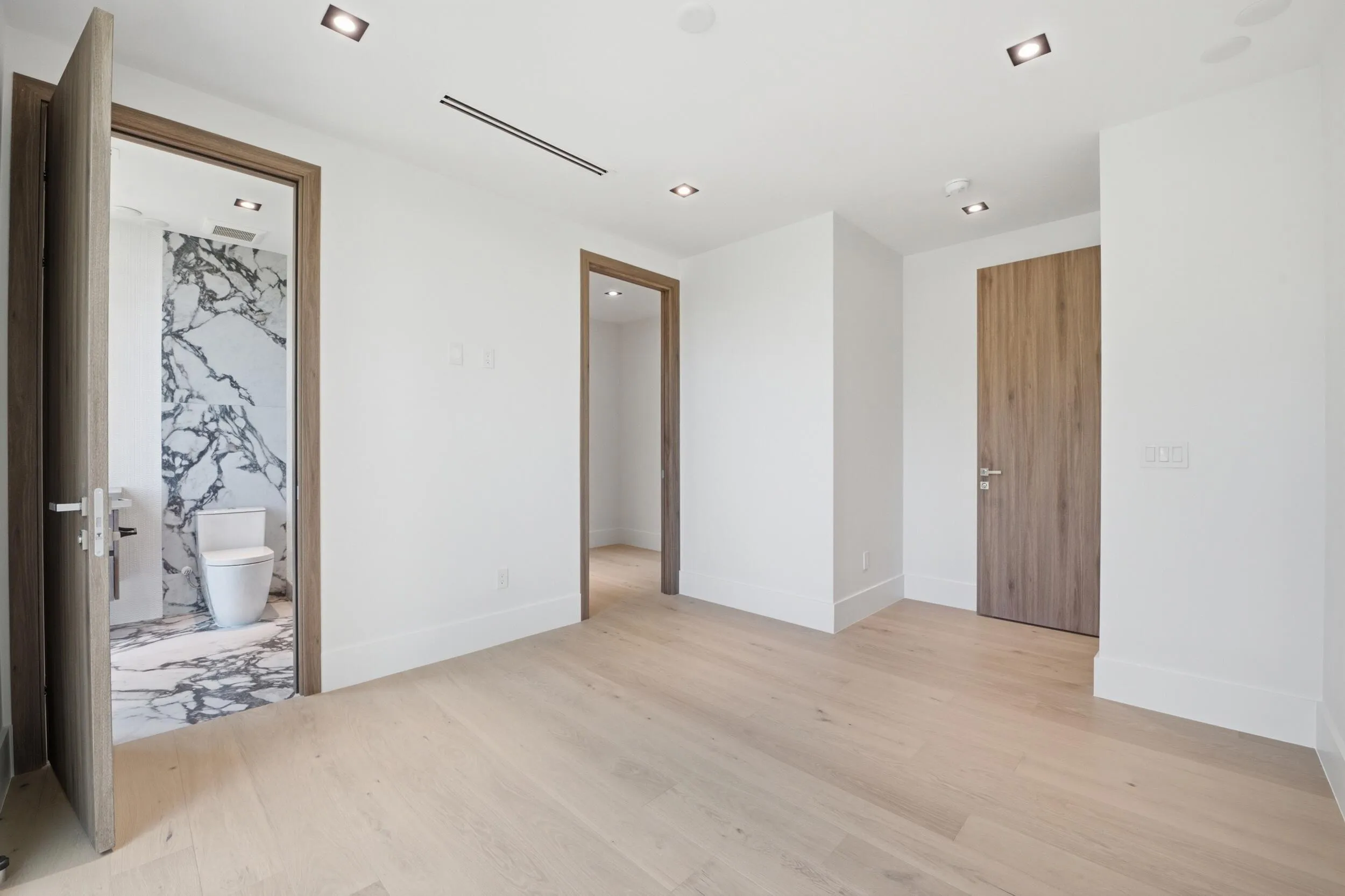 Light wood-finish flooring, recessed ceiling lighting, and solid wood interior doors