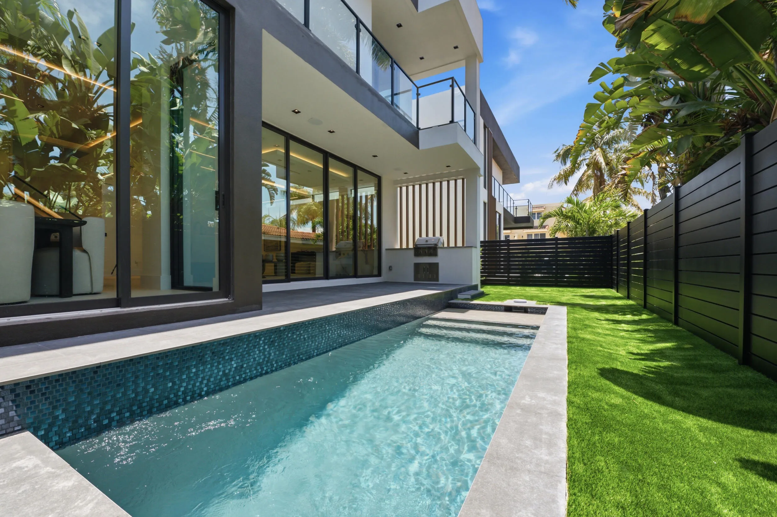 Modern exterior with a rectangular swimming pool, integrated spa steps, and a built-in outdoor grill station