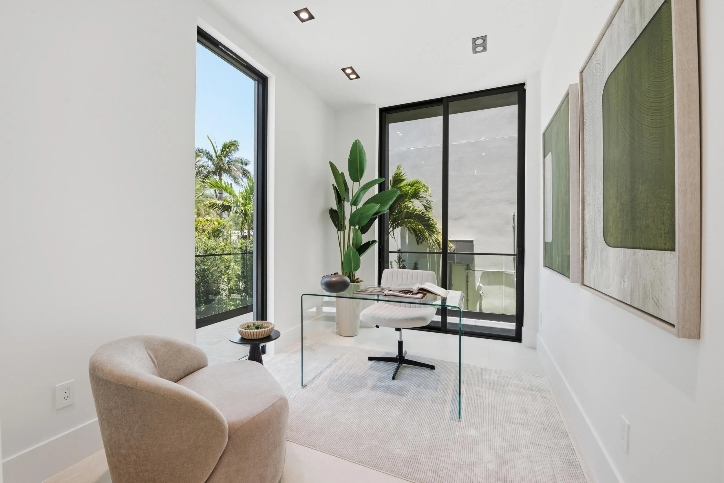 White interior walls, recessed ceiling lighting, light-toned flooring, and expansive windows with black framing