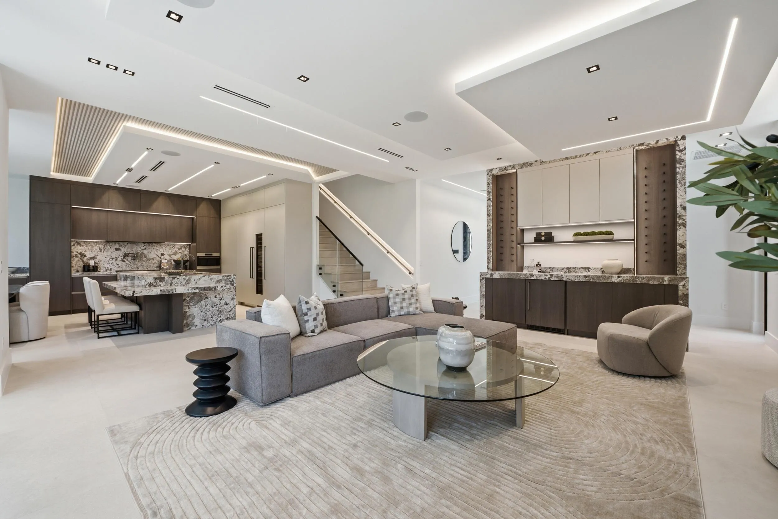 Open-concept living area with integrated kitchen, custom built-in bar, and a modern staircase