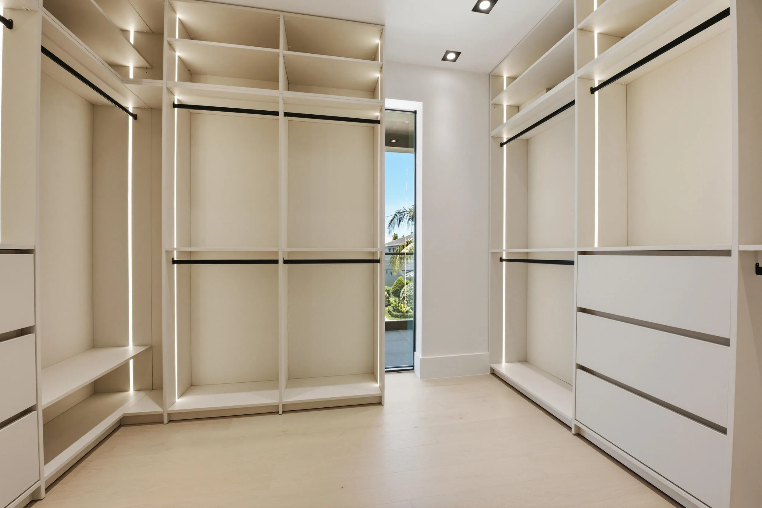 Custom built-in closet system with integrated lighting, multiple shelving units, hanging rods, and integrated drawers