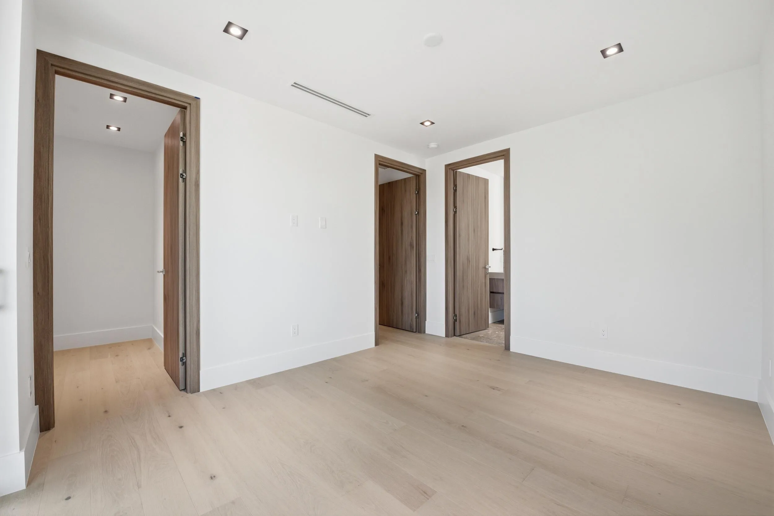 Light wood-finish flooring with crisp white walls and recessed ceiling lighting