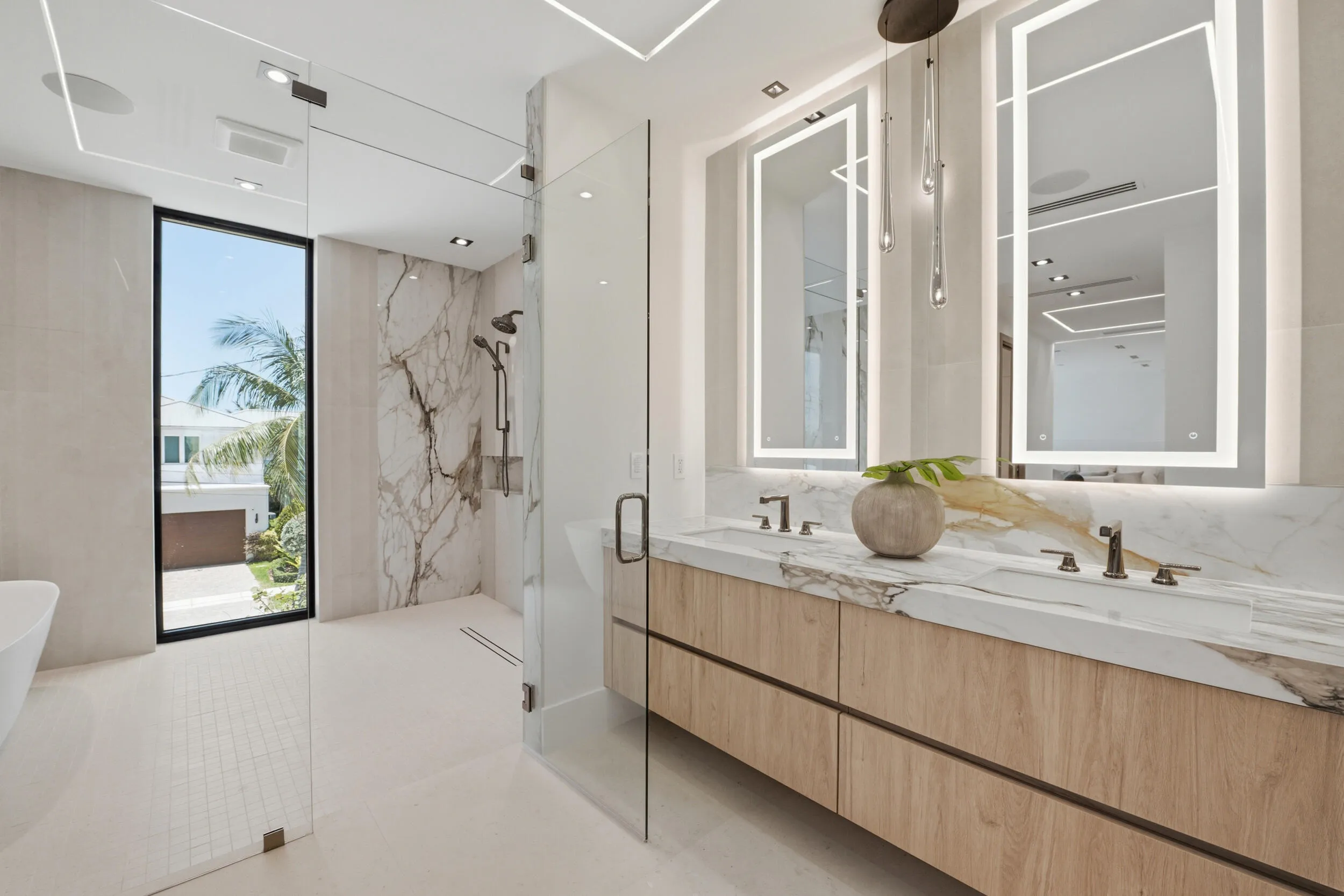 Dual floating vanity with wood-finish cabinetry, integrated sinks, and backlit mirrors