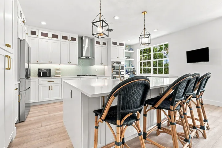 White shaker cabinetry with gold-tone hardware, stainless steel appliances and a central island with a solid surface countertop
