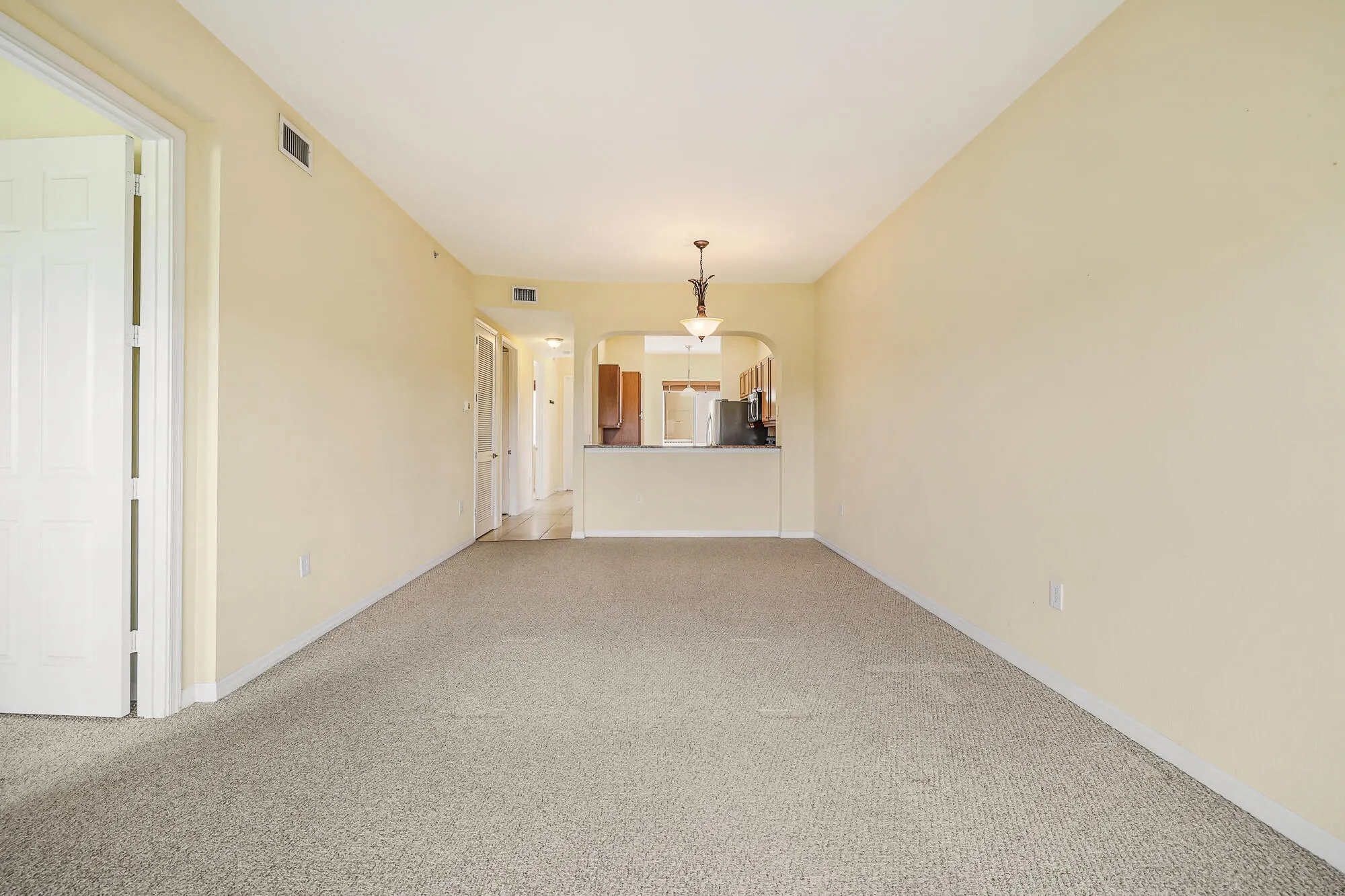 This is the living room with no furniture and carpet.